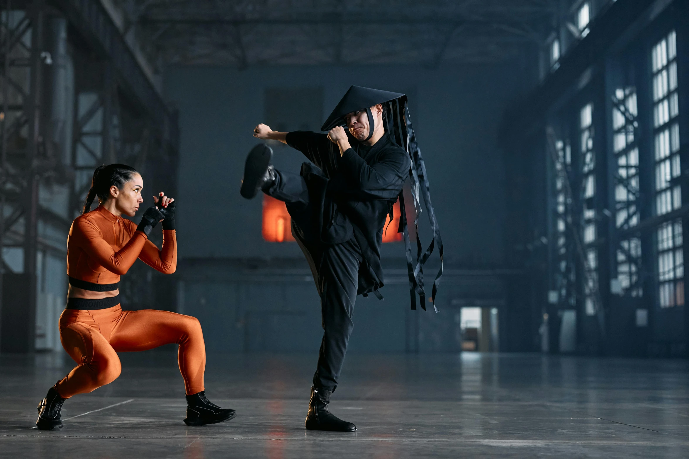 a couple of people standing on top of a cement floor, inspired by Ma Quan, in orange clothes) fight, wearing a black catsuit, vfx film, in a dojo