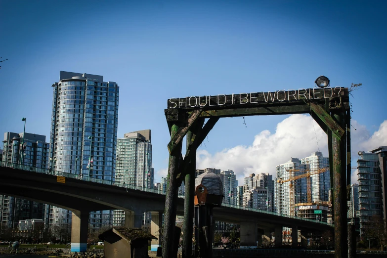 a bridge over a body of water with tall buildings in the background, by Chris Rallis, pexels contest winner, vancouver school, subject action : holding sign, world building, billboard image