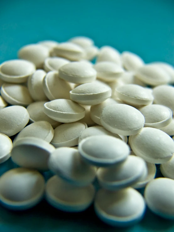 a pile of white pills sitting on top of a blue table, by Jason Felix, plasticien, labcoats, detailed product shot, vanilla, over the shoulder