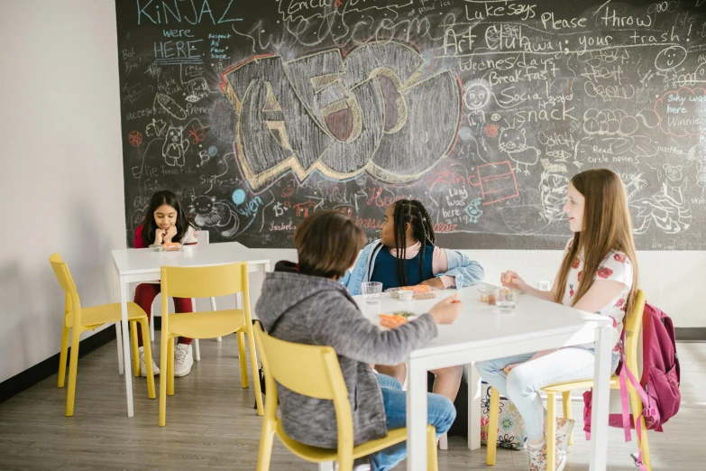 a group of girls sitting at a table in front of a blackboard, by Emma Andijewska, pexels contest winner, graffiti, pizza on a table, kids place, on a white table, thumbnail