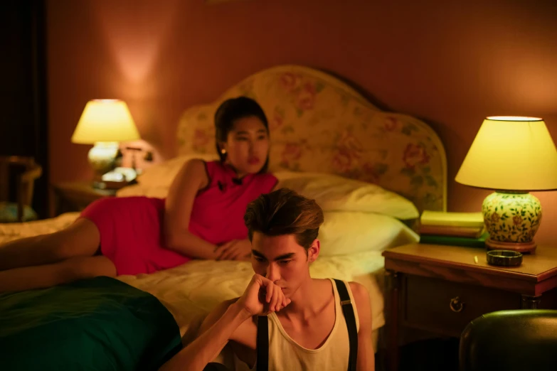 a man sitting on top of a bed next to a woman, inspired by Nan Goldin, trending on pexels, cai xukun, soft calm warm neon atmosphere, still image from tv series, retro stylised