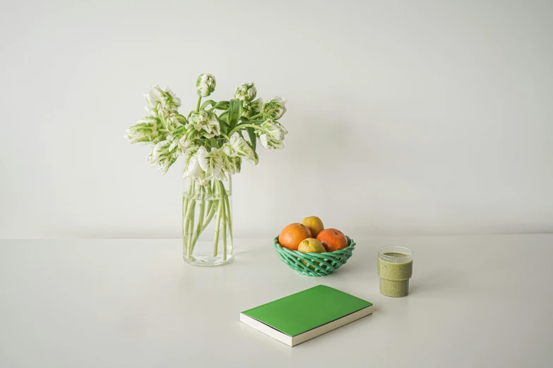 a vase of flowers and a book on a table, inspired by Art Green, minimalism, a fruit basket, green and white, full product shot, small