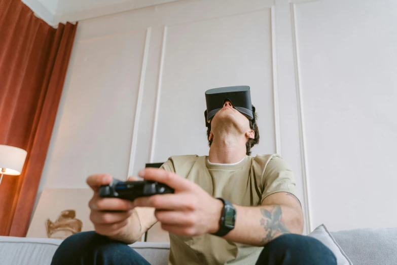 a man sitting on a couch holding a video game controller, a picture, trending on pexels, hyperrealism, goggles on forehead, visor over face, rectangle, 3 d goggles