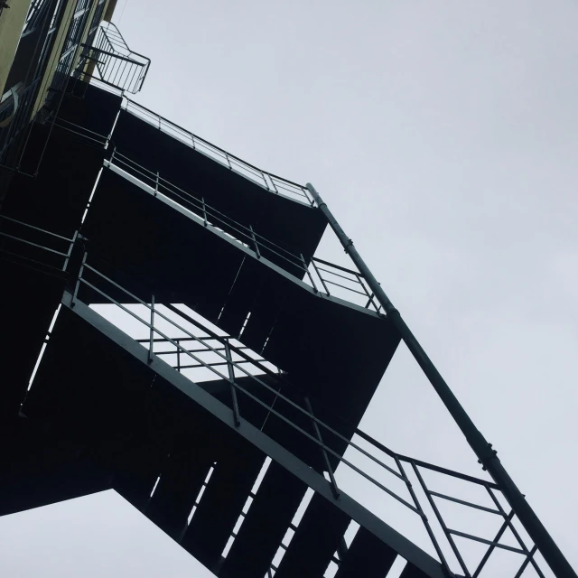 a tall tower with a clock on top of it, a photo, by Mathias Kollros, outdoor staircase, steel and metal, low quality photo, buildings covered in black tar