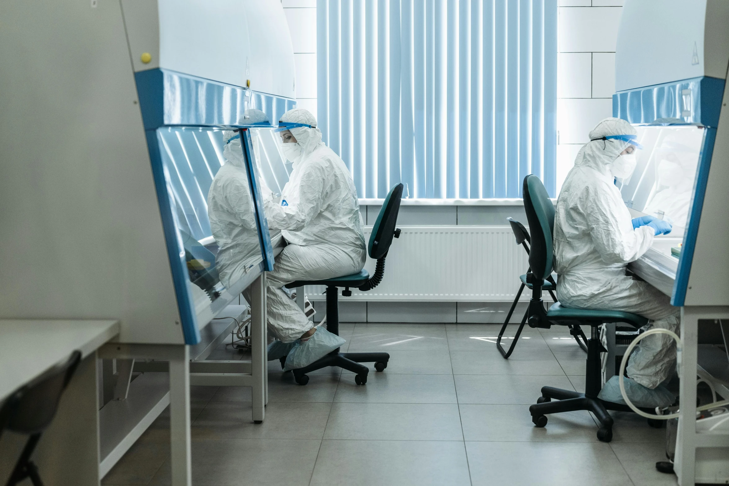 a group of people sitting at desks in a room, by Adam Marczyński, shutterstock, private press, staff wearing hazmat suits, wearing a lab coat, isolation, unedited