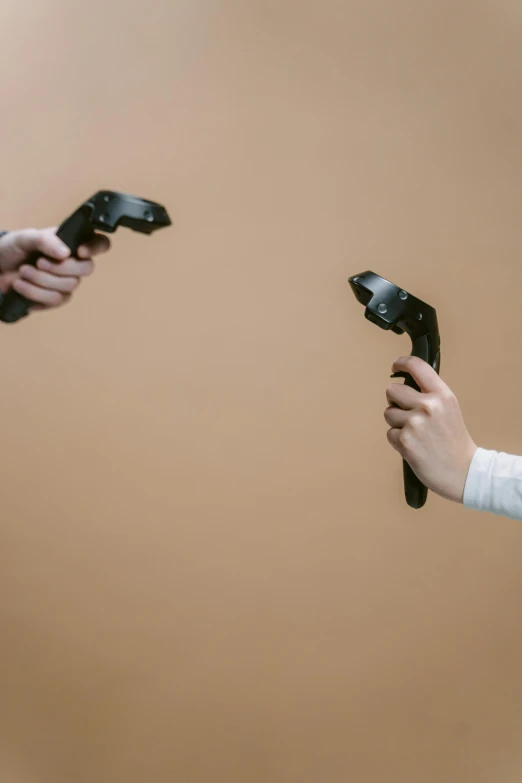 two people holding video game controllers in their hands, by Adam Marczyński, facing off in a duel, on a pale background, motion capture system, a high angle shot