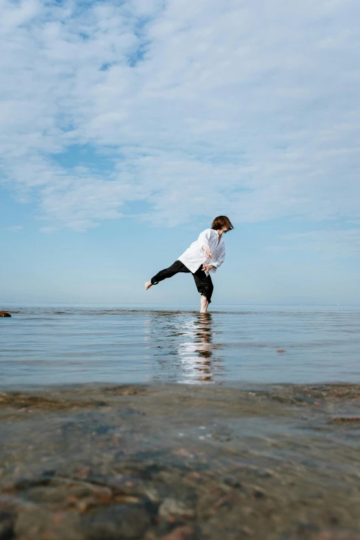 a couple of people that are standing in the water, by Nina Hamnett, unsplash, arabesque, little boy, doing a kick, standing on rocky ground, balance