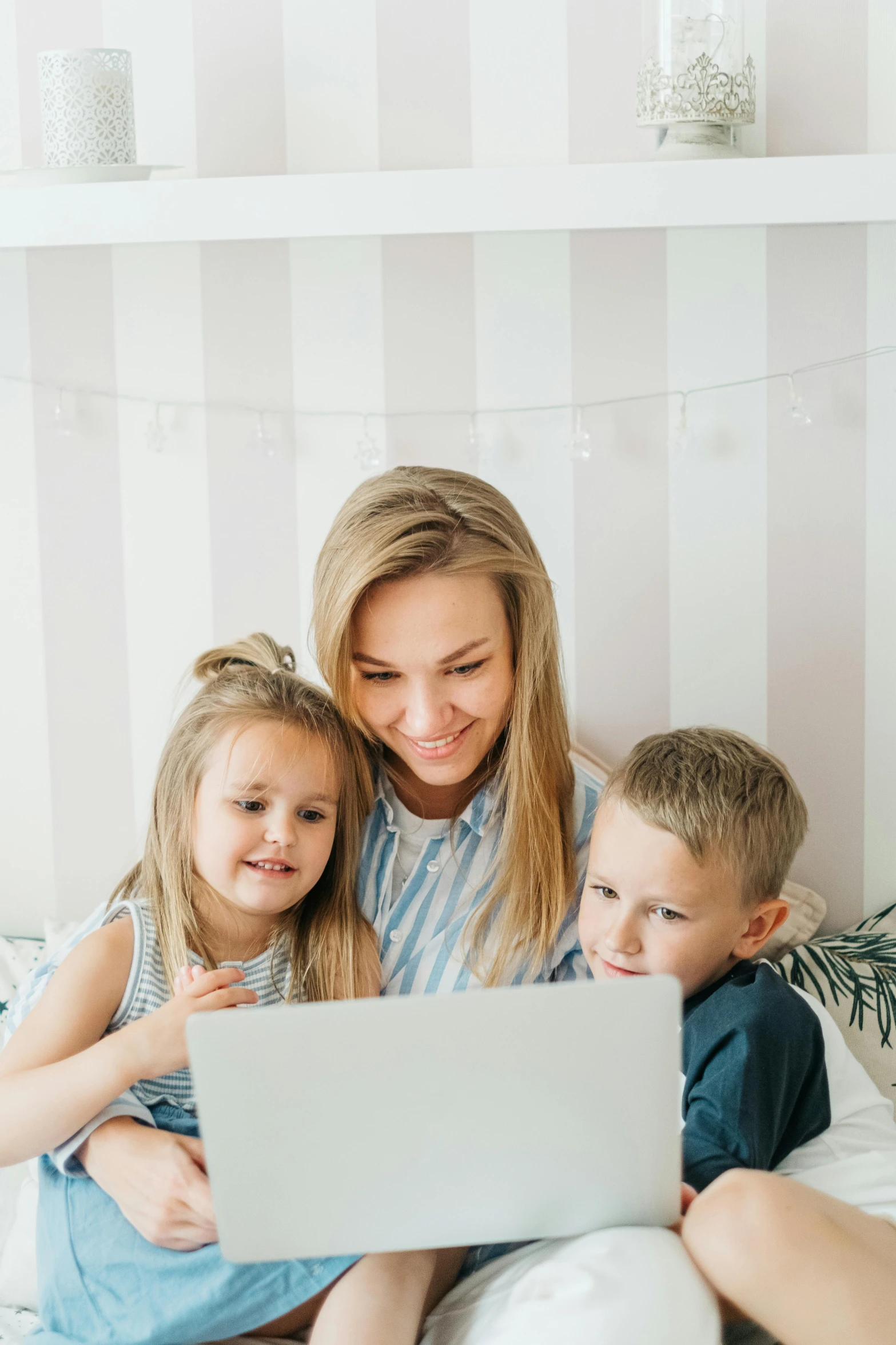 a woman and two children sitting on a bed looking at a laptop, pexels contest winner, a blond, gif, small, maintenance