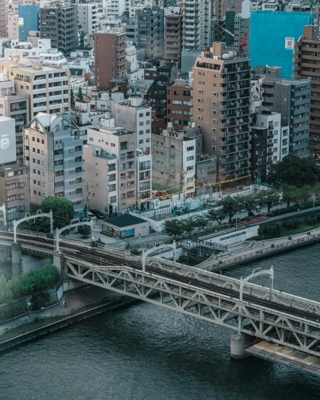 a train traveling over a bridge over a river, inspired by Takeuchi Seihō, pexels contest winner, tall buildings on the sides, overview, gif, japanese neighborhood