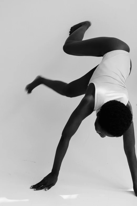 a black and white photo of a person doing a handstand, unsplash, arabesque, photo of a black woman, showstudio, wearing white leotard, spiraling