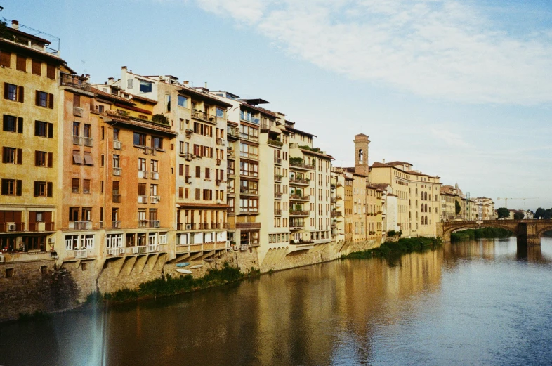 a river running through a city next to tall buildings, a photo, by Patrick Pietropoli, renaissance, medium format. soft light, florence, colour photograph, view from the side”