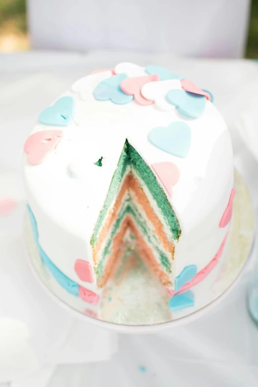 a cake sitting on top of a white table, inspired by Louis Hersent, color field, hearts, pregnancy, layer upon layer, pink and blue and green mist