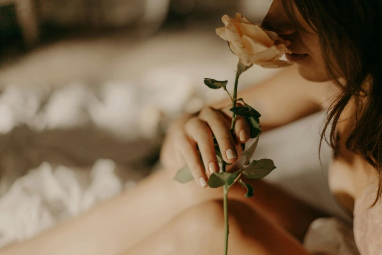 a woman sitting on a bed holding a flower, trending on pexels, profile image, rose twining, background image, delicate fingers