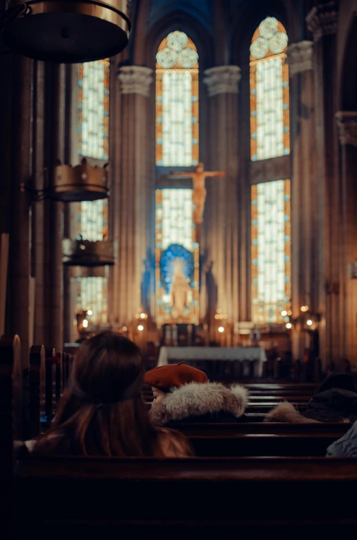 a couple of people that are sitting in a church, facing away from the camera