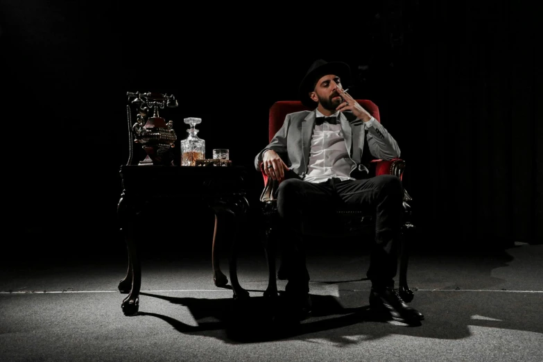 a man sitting in a chair smoking a cigarette, inspired by William Grant Stevenson, pexels contest winner, baroque, on a stage, drinks bourbon, professional photo shoot, josh grover