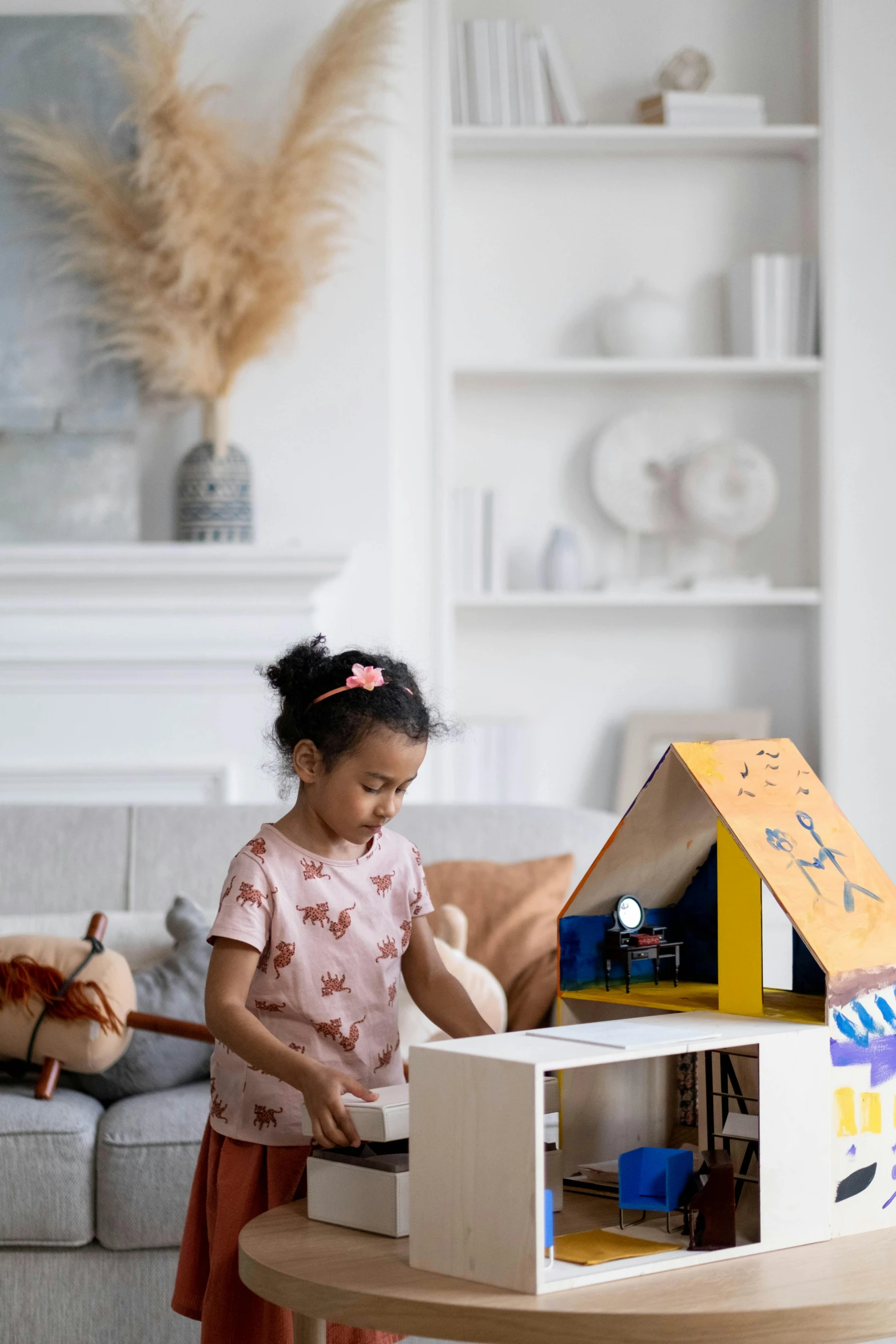 a little girl standing in front of a doll house, a child's drawing, inspired by The Family Circus, blue theme and yellow accents, detailed product image, pokimane, in a living room