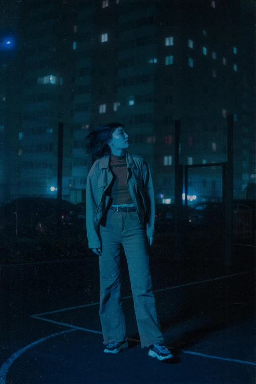 a man standing on a basketball court at night, an album cover, inspired by Elsa Bleda, pexels contest winner, realism, photo of young woman, wearing a blue jacket, ( ( theatrical ) ), night city