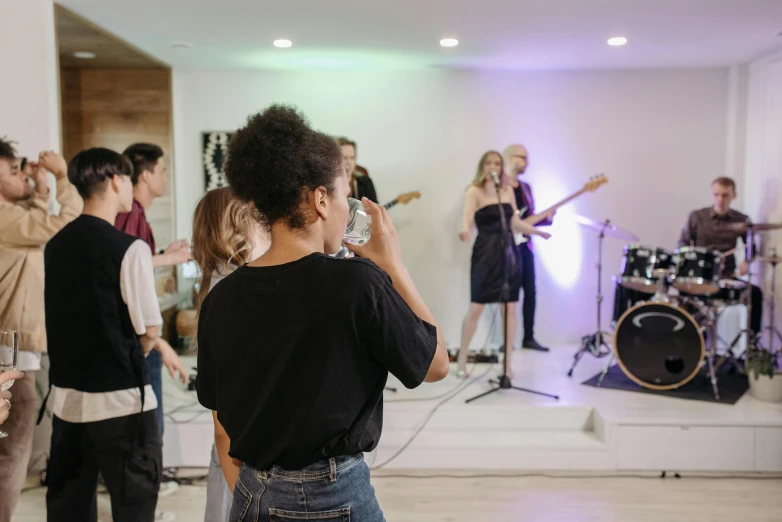 a group of people that are standing in a room, singing, profile image, performing a music video, background image
