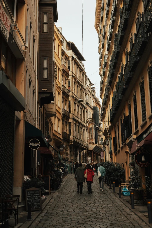 a couple of people walking down a cobblestone street, a picture, tall buildings, turkey, stacked image