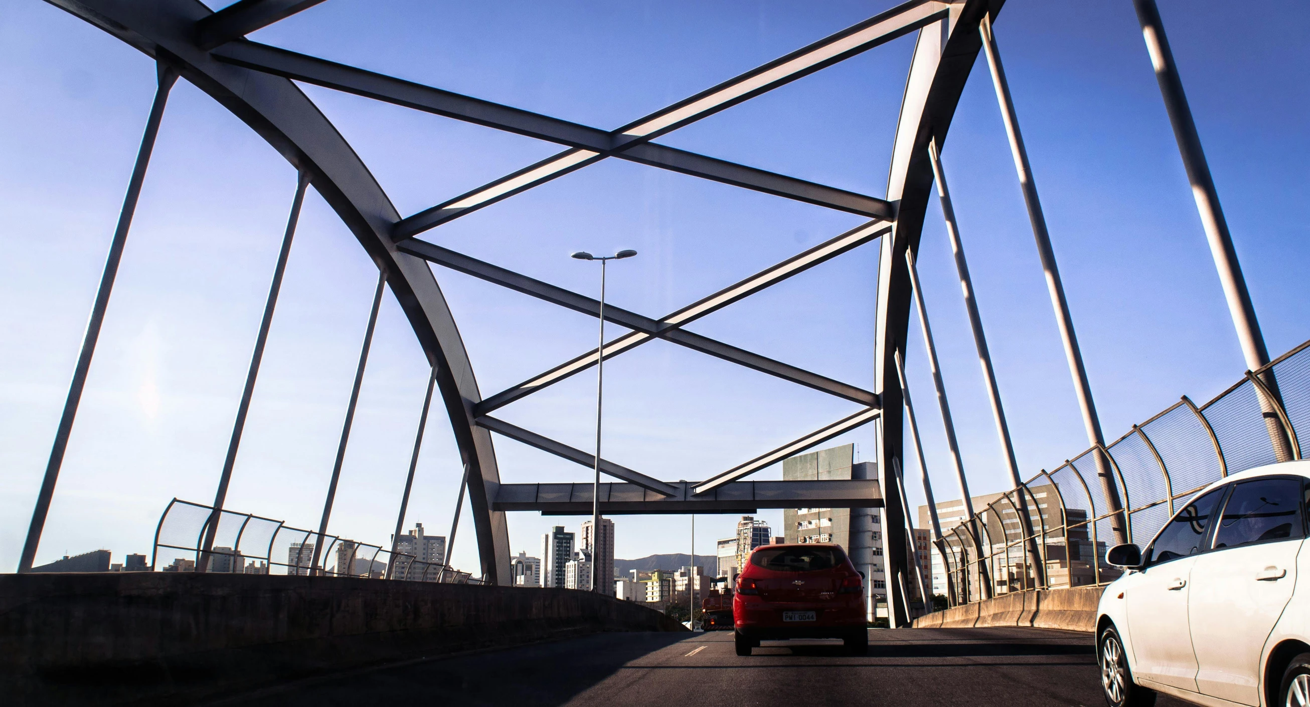 a car driving across a bridge on a sunny day, by Ceferí Olivé, pexels contest winner, hypermodernism, steel archways, sao paulo, walking over a tiny city, dramatic ”