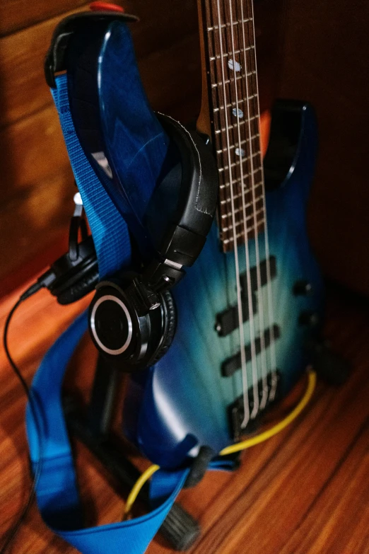 a blue guitar sitting on top of a wooden floor, wearing black headphones, bassist, thumbnail, premium