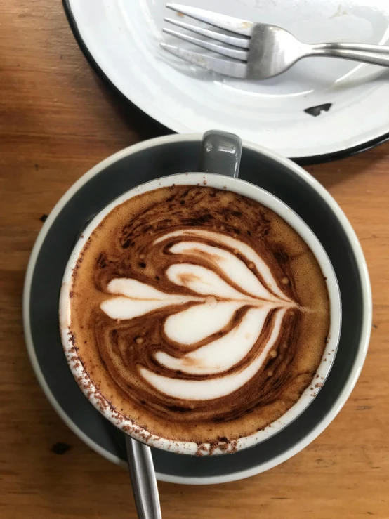 a cup of coffee sitting on top of a wooden table, by Susy Pilgrim Waters, manly, fully chocolate, thumbnail, latte art