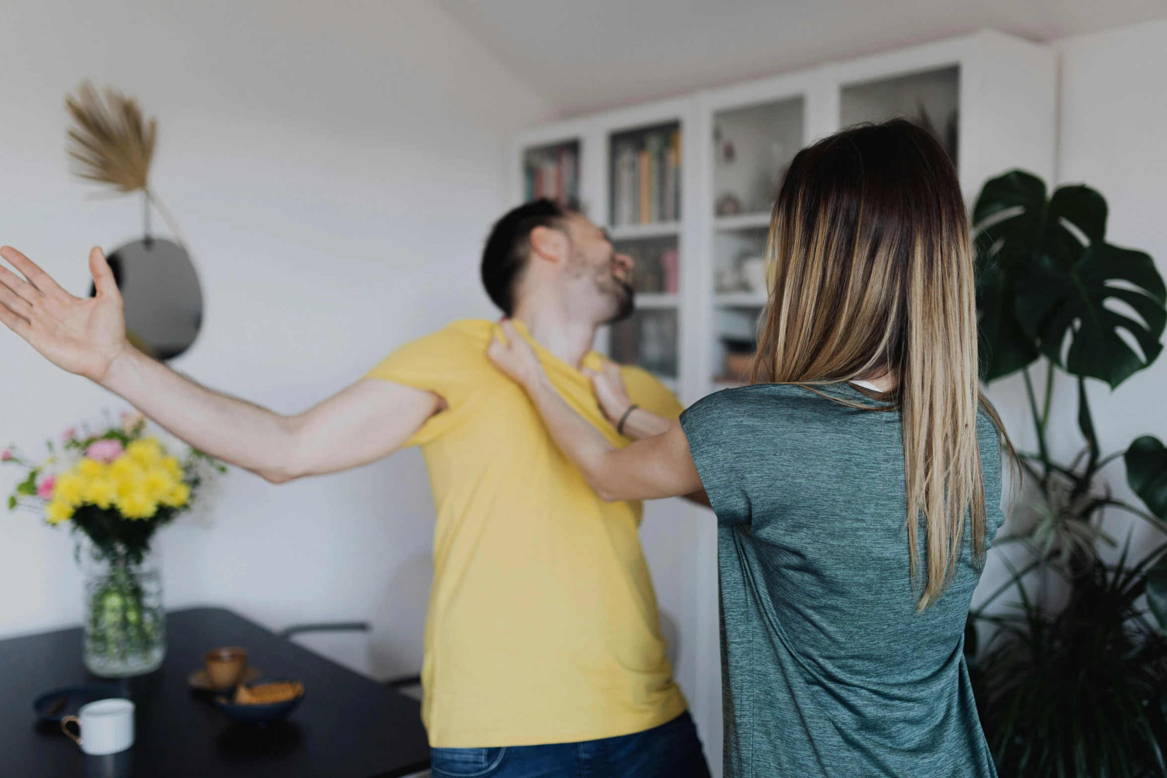 a man and a woman standing in a living room, fighting posture, leesha hannigan, background image, shot from the back