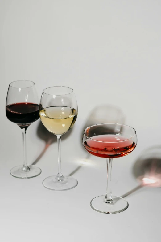 three glasses of wine sitting next to each other, pexels, on a pale background, multiple stories, sydney hanson, chromatic