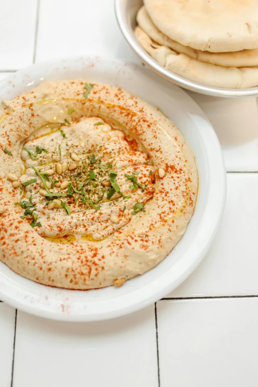 a white plate topped with hummus and pita bread, by Will Ellis, bowl, bagels, daily specials, david kassan