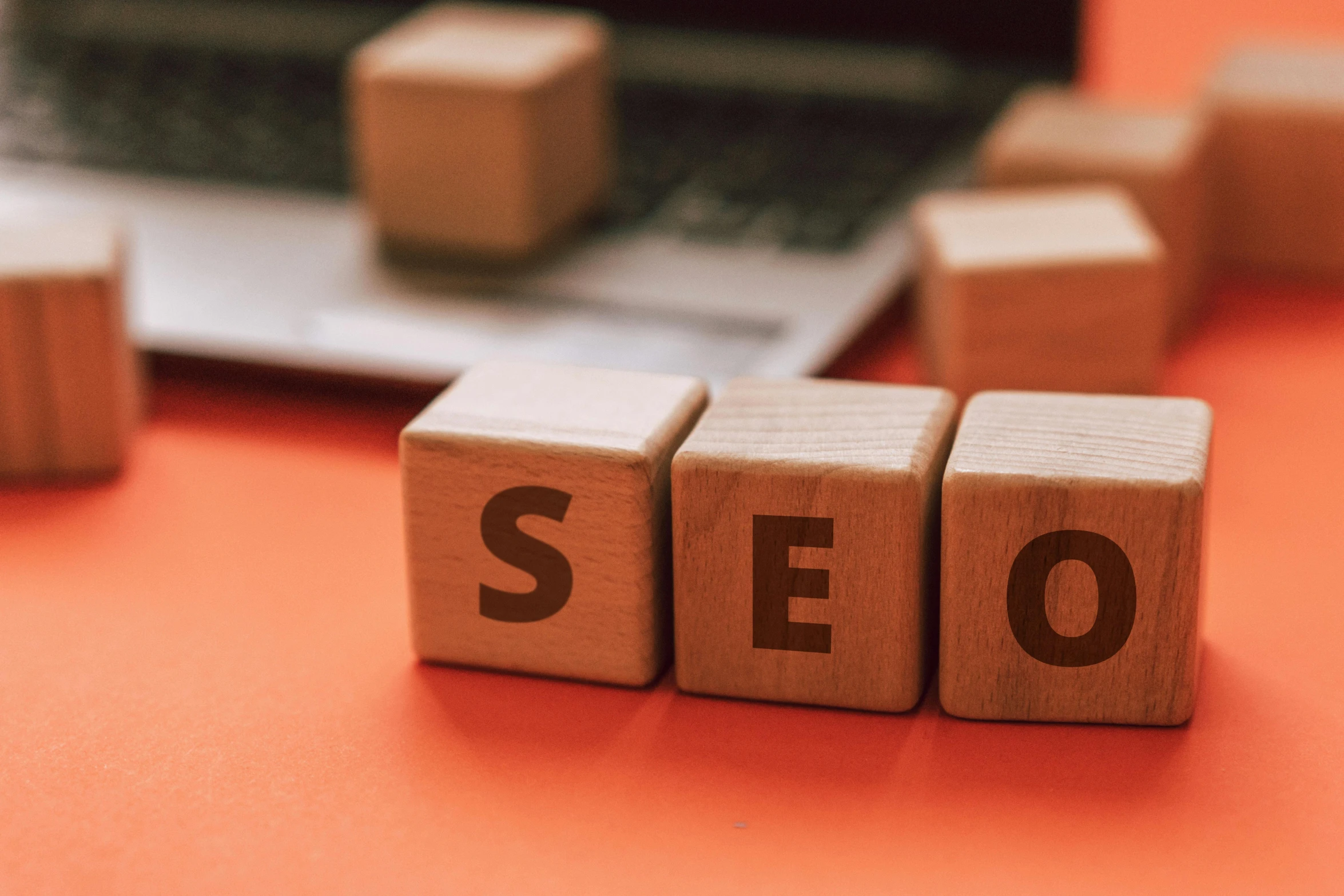 wooden blocks spelling seo with a laptop in the background, trending on pexels, hurufiyya, in front of an orange background, square, ron cobb, sam leach