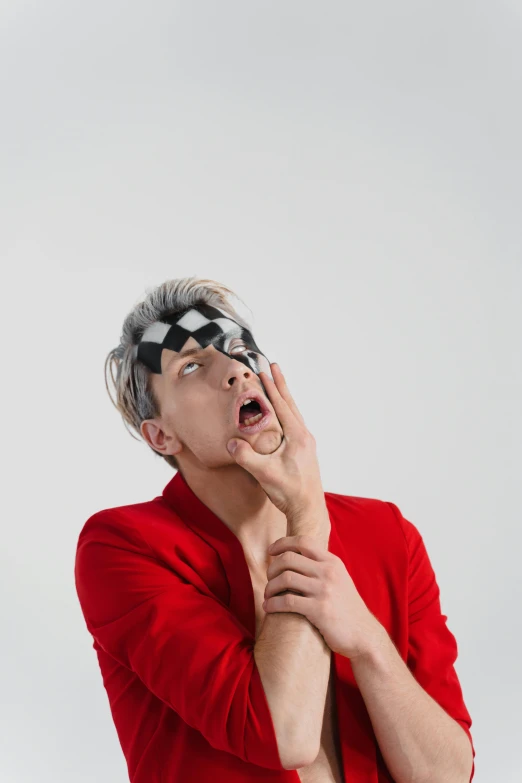 a man in a red shirt is making a funny face, an album cover, by artist, trending on pexels, altermodern, xqc, blindfold, silver monocle, checkered spiked hair