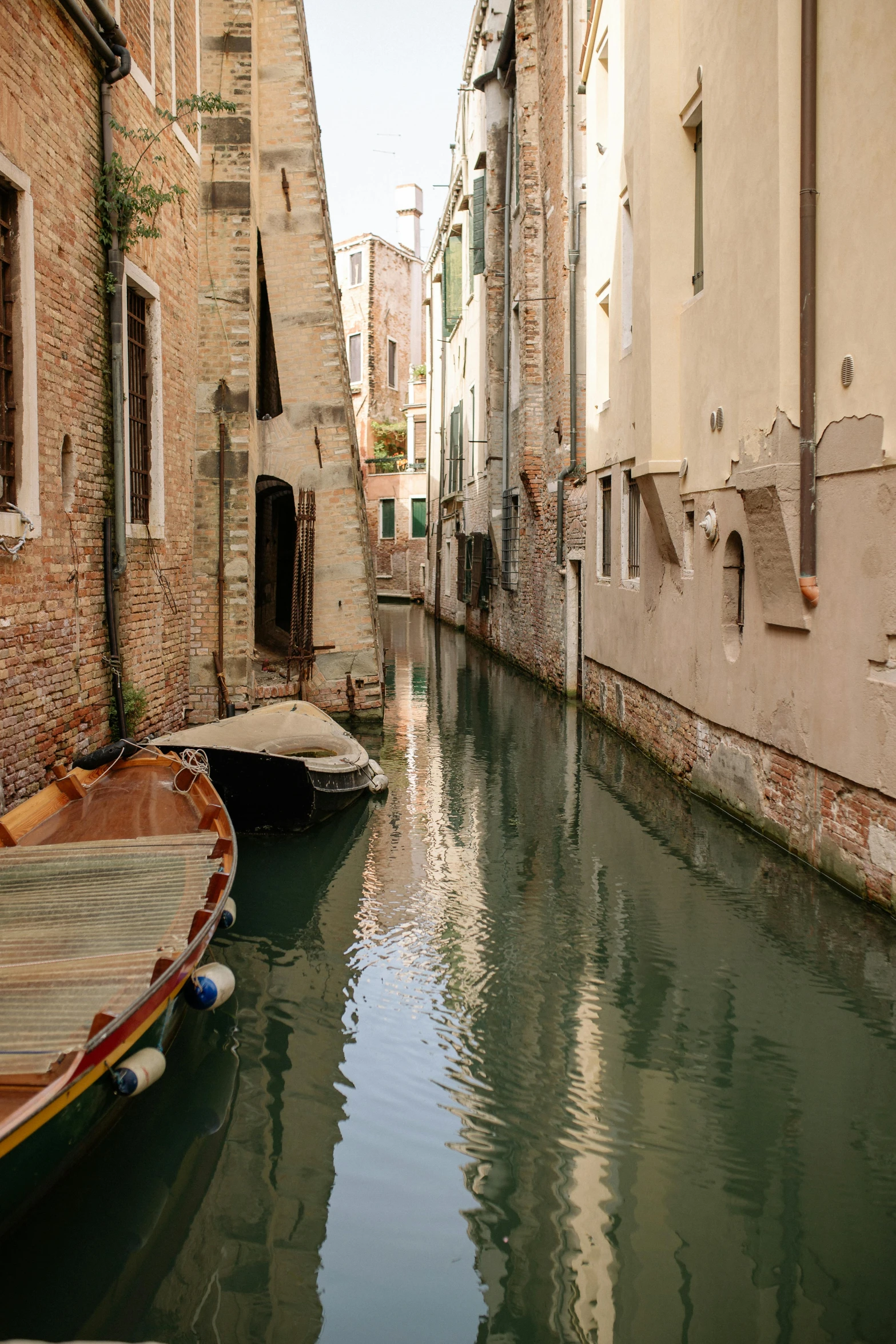 a couple of boats sitting on the side of a river, by Carlo Martini, pexels contest winner, renaissance, shady alleys, calm, small flowing stream from wall, 2022 photograph