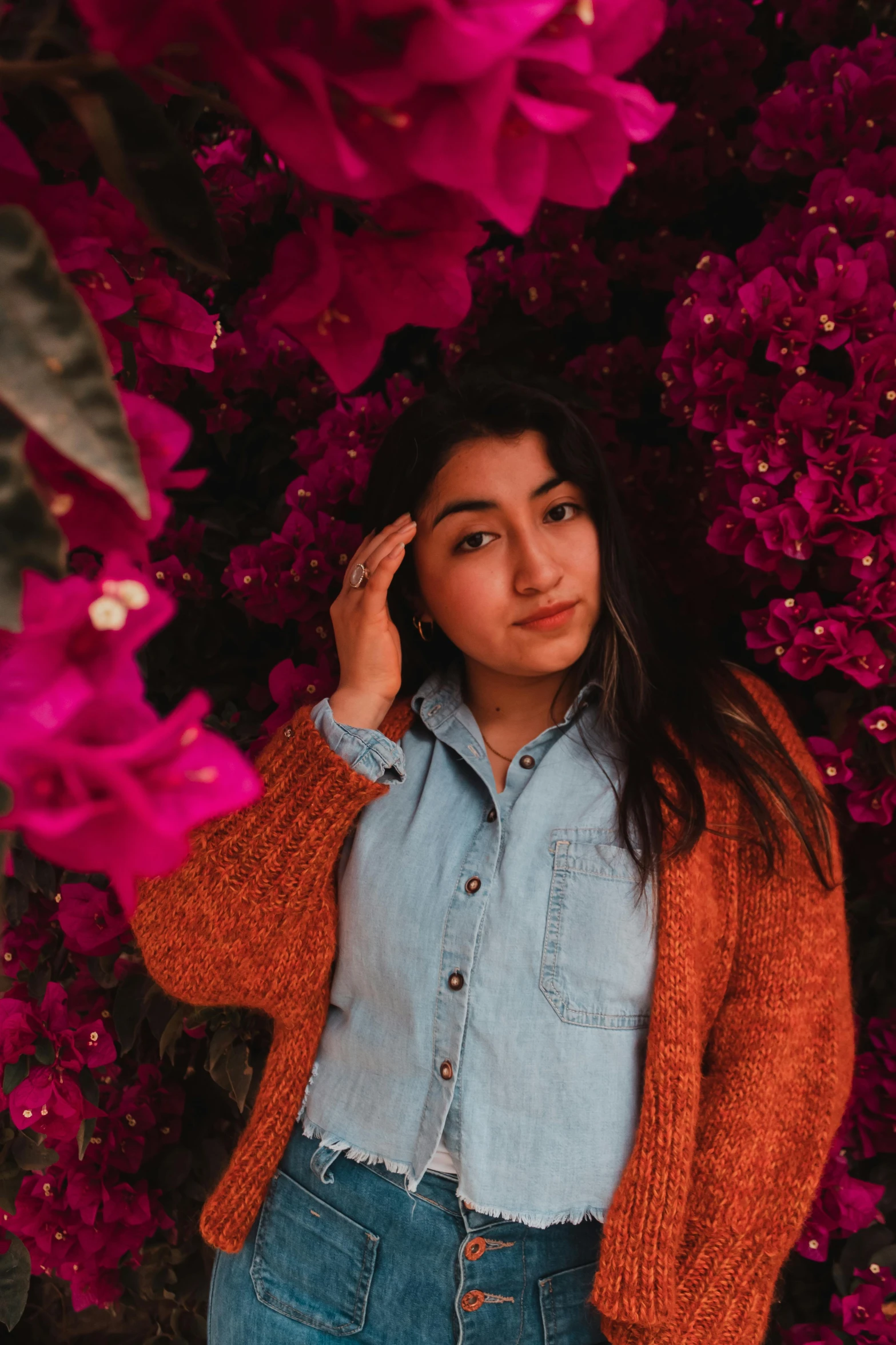 a woman standing in front of purple flowers, by Robbie Trevino, avatar image, wearing casual clothing, bougainvillea, indoor picture