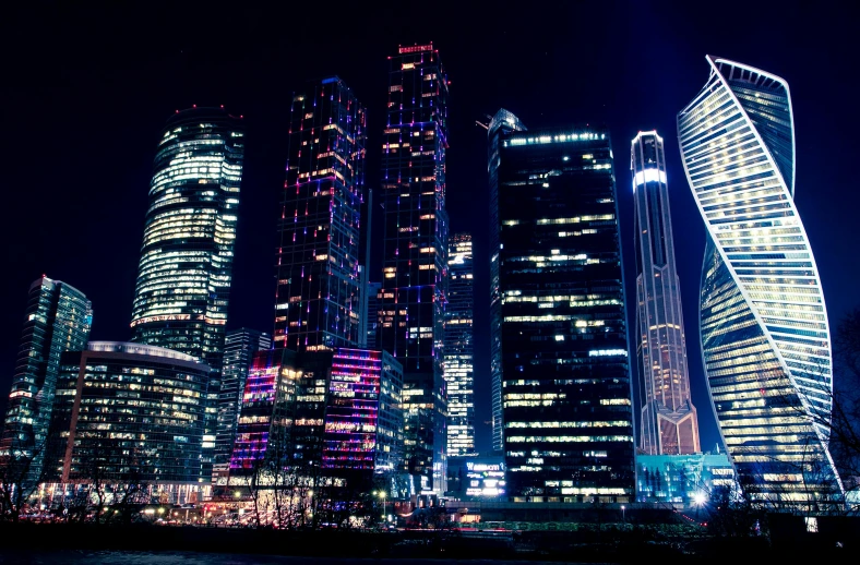 a group of skyscrapers lit up at night, by Andrei Kolkoutine, sanctions in russia, innovative, city background, instagram post