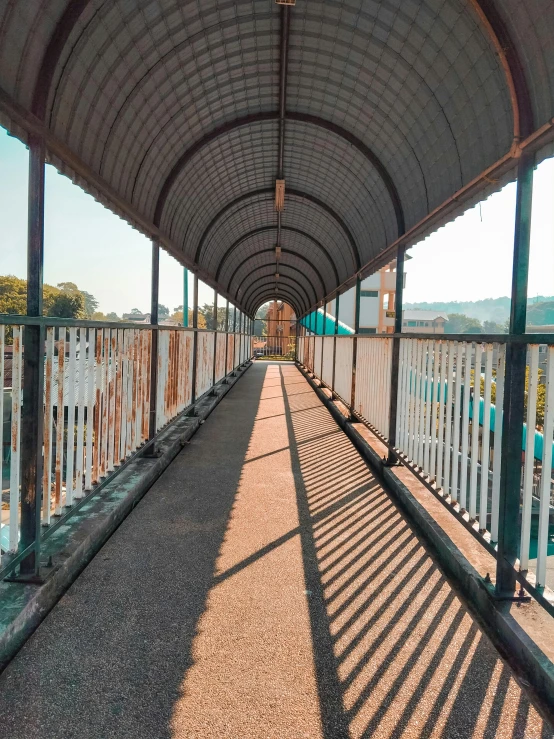 a long walkway next to a body of water, long street, harsh overhead sunlight, railing, in the center of the image