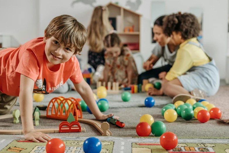 a group of children playing with toys on the floor, by Alexander Brook, pexels contest winner, looking across the shoulder, coloured, lachlan bailey, in a classroom