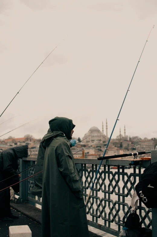 a group of people standing on top of a bridge, pexels contest winner, hurufiyya, fishing, fallout style istanbul, hooded, low quality photo