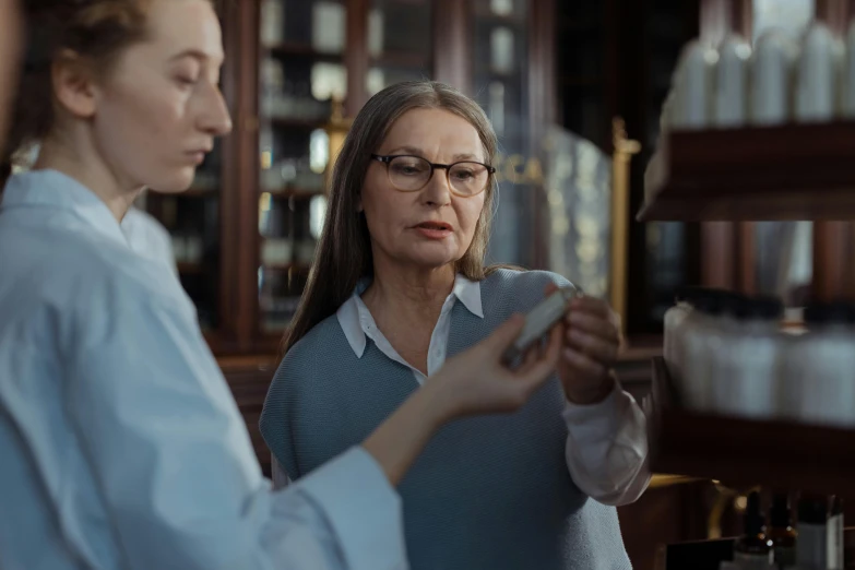 two women standing next to each other in a store, a portrait, by Emma Andijewska, pexels contest winner, analytical art, medical lab, 2 0 2 1 cinematic 4 k framegrab, specimens in glasses, older woman