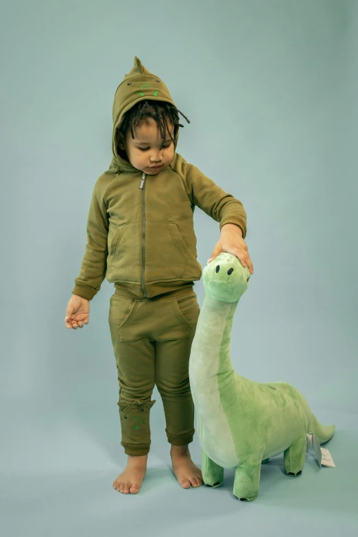 a small child standing next to a stuffed animal, inspired by Abidin Dino, tracksuit, olive green, full body close-up shot, lookbook