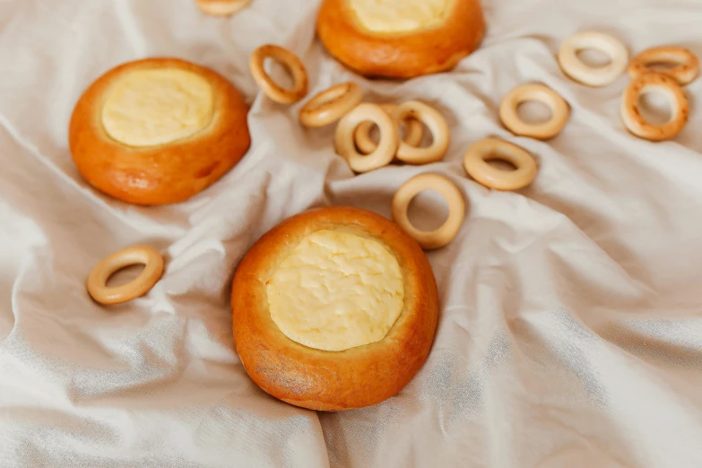 a group of pretzels sitting on top of a white sheet, inspired by Károly Patkó, mingei, flan, made of cheese, soft round features, close up iwakura lain