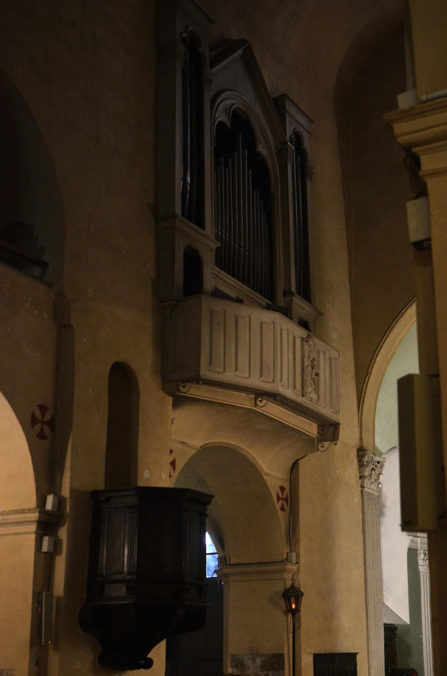 a large pipe organ hanging from the side of a building, by Cagnaccio di San Pietro, poorly lit, entrance, nice, opposite the lift-shaft