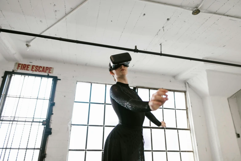 a woman in a black dress standing in front of a window, a hologram, by Nina Hamnett, unsplash, interactive art, wrestlers wearing vr headsets, a woman floats in midair, like a cyberpunk workshop, sydney hanson