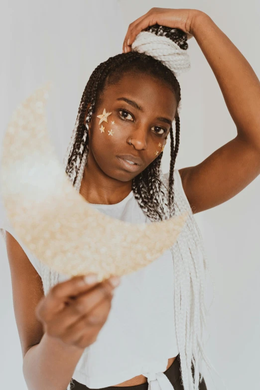 a woman wearing a white top and black shorts, trending on pexels, afrofuturism, standing in gold foil, crescent moon, frosting on head and shoulders, white freckles