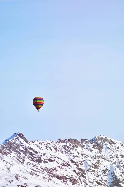 a hot air balloon flying over a snow covered mountain, a photo, inspired by Eva Gonzalès, minimalism, colorful”, color”