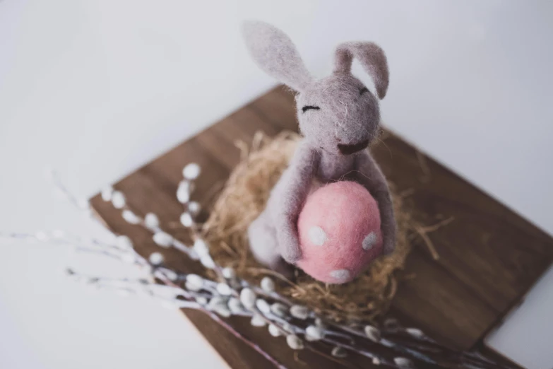 a stuffed rabbit sitting in a nest with a pink egg, by Emma Andijewska, pexels contest winner, cafe for felted animals, vignette, grey, 1614572159