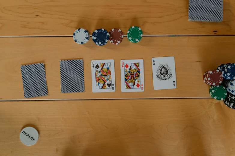 a wooden table topped with playing cards and poker chips, a screenshot, by Mathias Kollros, photograph from above, facing off in a duel, over-the-shoulder shot, poor quality