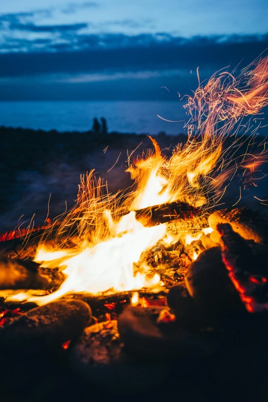 a person sitting in front of a campfire at night, pexels contest winner, ocean of canvas catching fire, flirting, field on fire, sparks and thunders