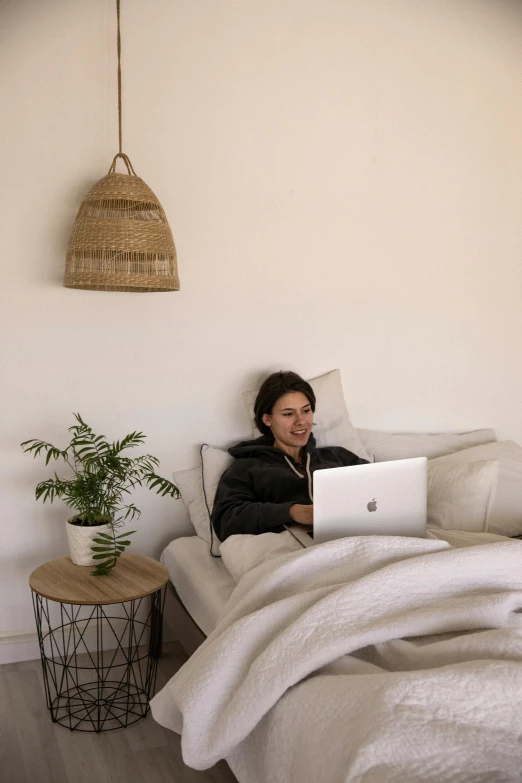 a woman sitting on a bed using a laptop, by Liza Donnelly, happening, lachlan bailey, cozy room, profile image, moroccan