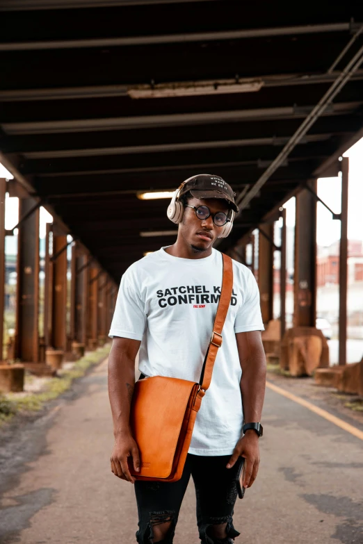 a man standing on a street holding a bag, an album cover, inspired by Barthélemy Menn, unsplash contest winner, black arts movement, man in white t - shirt, orange shoulder pads, holding a leather purse, in savannah