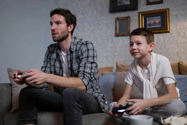 a man and a boy sitting on a couch playing a video game, pexels, hyperrealism, 15081959 21121991 01012000 4k, ea sport, looking towards camera, simon stalberg
